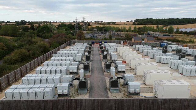 Close aerial flyover of modular battery energy storage units and high-voltage 400kV electrical substation equipment in Stony Stratford, UK