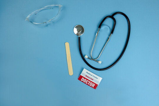 Black stethoscope and laboratory specimen tubes arranged on a clean blue background, creating a clear healthcare concept. The composition represents medical examination, diagnosis, clinical care, labo