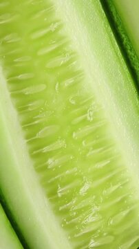 Fresh long cucumber sliced lengthwise showing flesh texture, slowly rotating. Extreme close-up shot