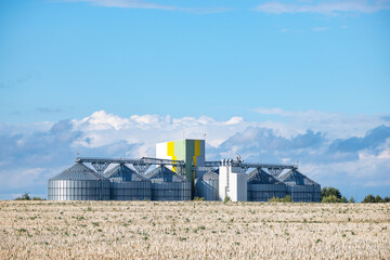 Modern grain silos and storage facility on farmland with beautiful cloudy sky © Cristi