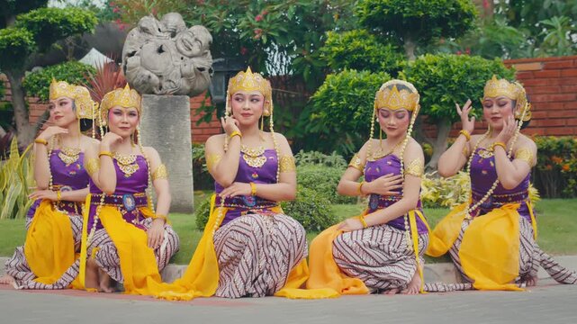 Row of Dancers Sitting Outdoors with Hand on Chest Gesture