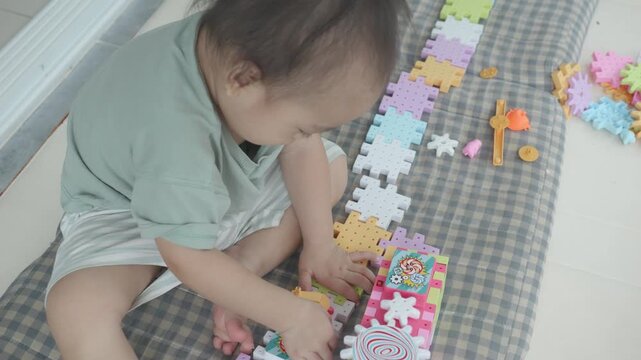 A toddler enthusiastically explores colorful puzzle pieces on a play mat, developing fine motor skills and creativity. The vibrant shapes and textures invite imaginative play, fostering cognitive deve