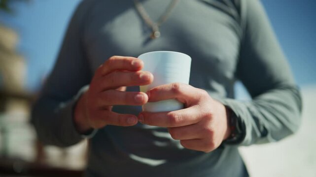 A person holds a white cup and gestures with an open hand in a bright outdoor setting. This captures a casual moment of connection and conversation among friends during winter.