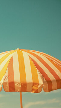 yellow and white striped beach umbrella against turquoise background, minimalist summer vacation photography with copy space for travel advertising, poster or seasonal design