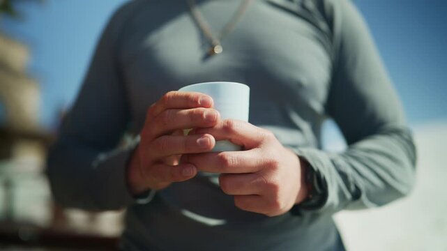 A person holds a warm cup with both hands, enjoying a comforting beverage. This scene evokes the feeling of warmth and connection during winter time with friends.