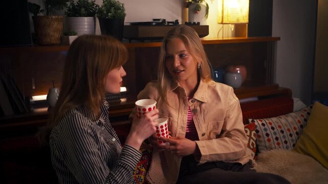 Close friends sharing secrets and talking in a cozy home setting evening