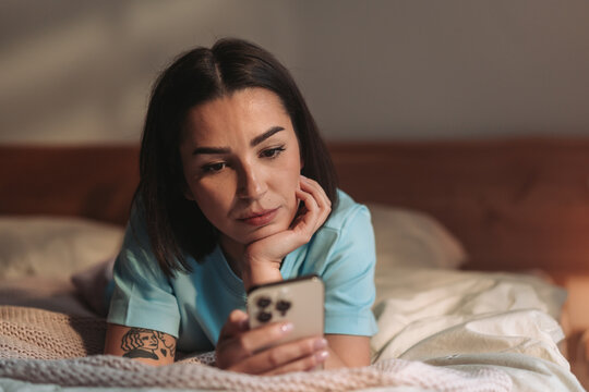Tranquil Woman Engaged In Her Digital Work While Resting In Wellorganized And Softly Lit Bedroom Environment