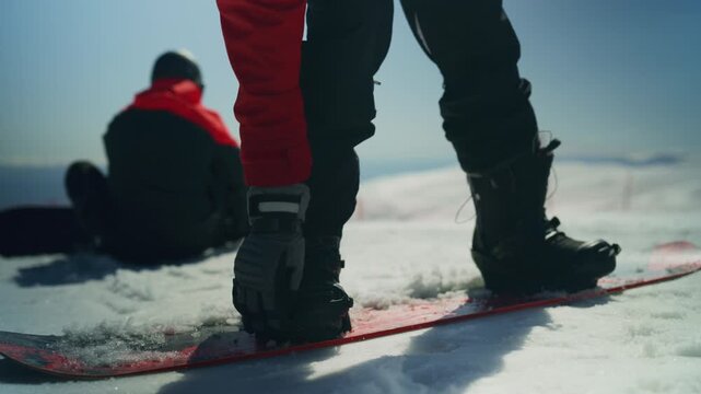 Snowboarders prepare their equipment on a pristine snow-covered mountain. Friends enjoy an active winter time amidst breathtaking snowy peaks.