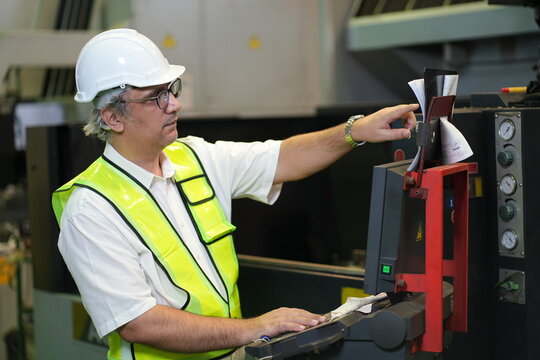 Male industrial worker operating machine control panel in modern manufacturing factory
