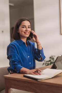 A Professional Woman Dressed in a Blue Shirt Taking a Phone Call While at Work