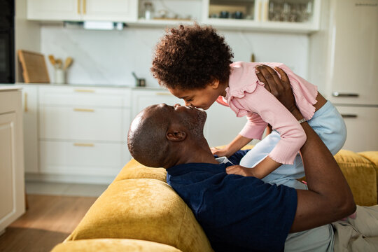 Father and daughter playing on sofa at home