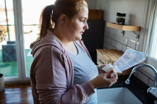 Worried woman reading utility bills in home kitchen