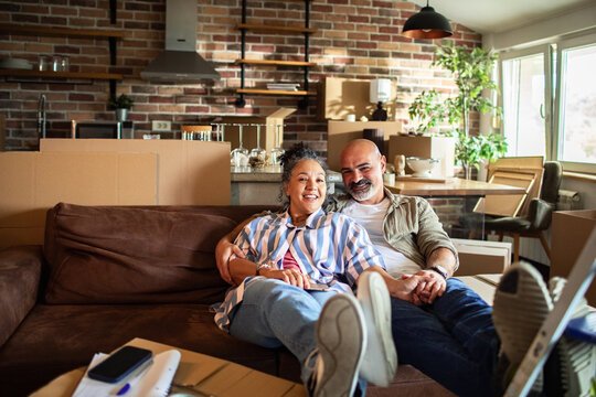 Happy mature couple relaxing on sofa in new home living room