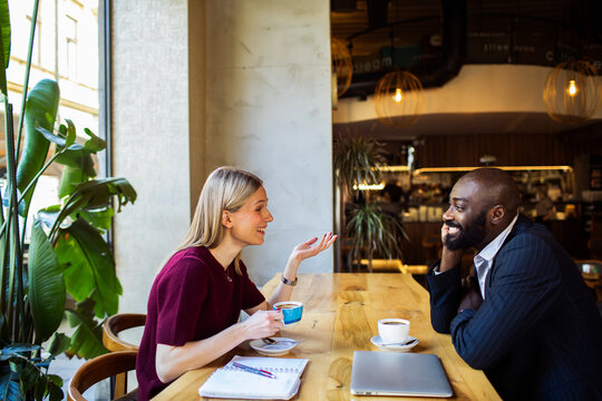 Colleagues having coffee and conversation in modern cafe