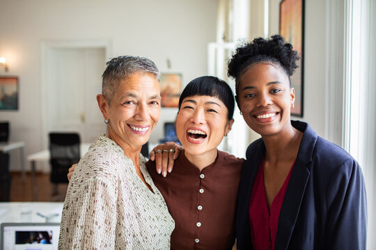 Smiling women colleagues standing together in modern office