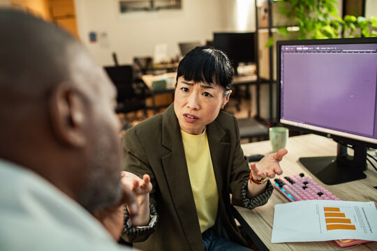 Concerned businesswoman discussing project issues with colleague in modern office