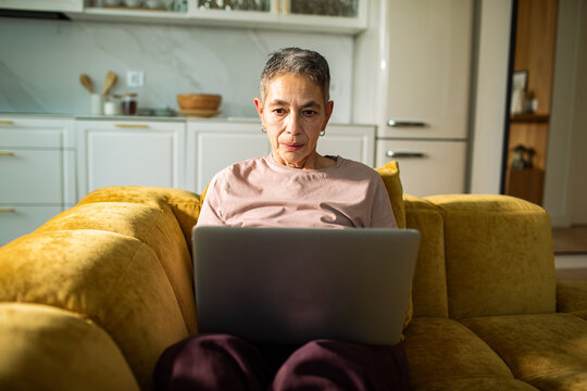 Older woman using laptop on sofa at home