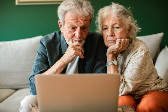 Senior couple looking at laptop on couch at home