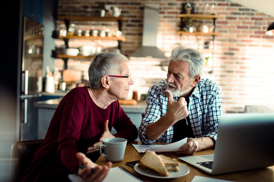 Senior couple reviewing bills at home kitchen table