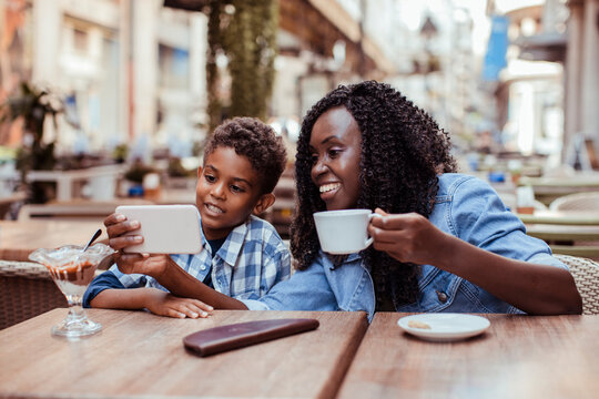 Mother and son watching smartphone at outdoor cafe