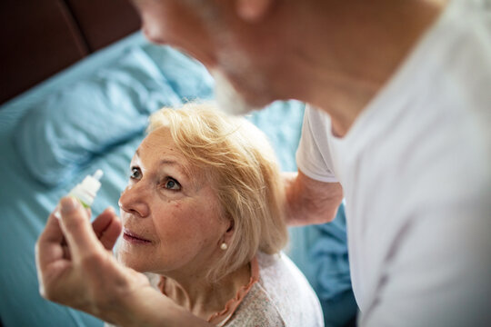 Senior woman receiving eye drops at home