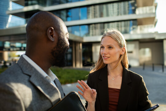 Two business professionals discussing project outside modern office