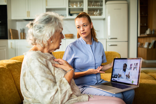 Caregiver assists senior with telemedicine consultation at home