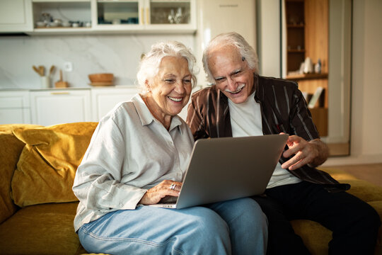 Happy senior couple using laptop at home