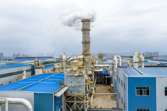 Blue factory building chimney emitting white smoke into the sky