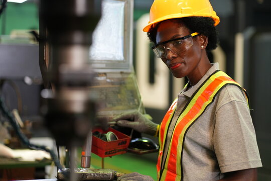 Female industrial worker inspecting CNC machining process with flashlight in manufacturing factory