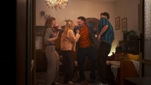 Group of friends dancing and celebrating at house party in living room