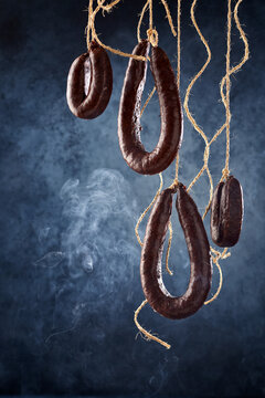 Cured blood sausage hanging and smoking in darkness
