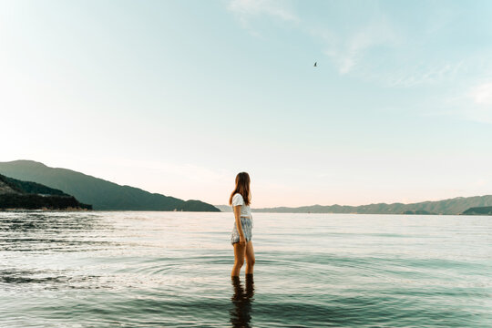 Woman standing by the sea at sunset