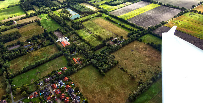 Aerial view of rural landscape and scattered houses near gifhorn, germany, with plane wing in foreground