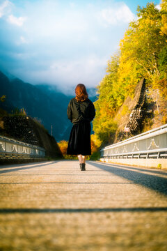 Woman jogging along a tree-lined park path in autumn