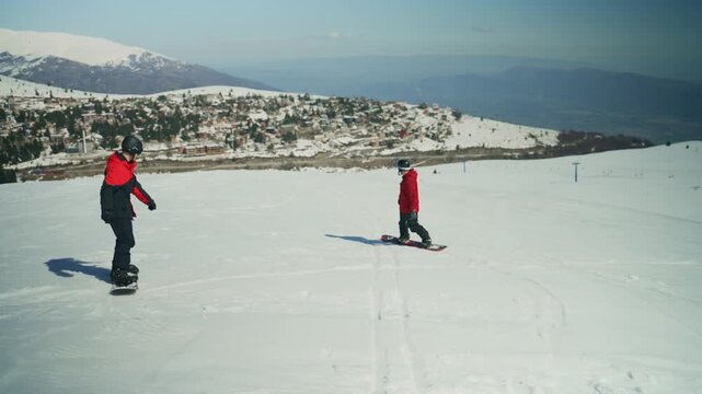 Two snowboarders glide gracefully down a snowy mountain. They enjoy their winter sport against a scenic alpine backdrop.