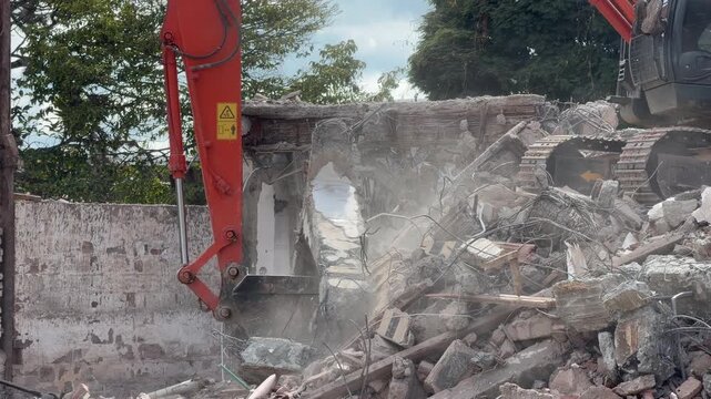 excavator demolishing a building and clearing rubble