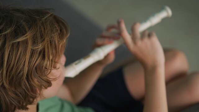 A little boy learns to play the flute at home, practicing with focus and enthusiasm in a cozy, warm setting. A charming scene of early musical exploration, creativity, and childhood growth.