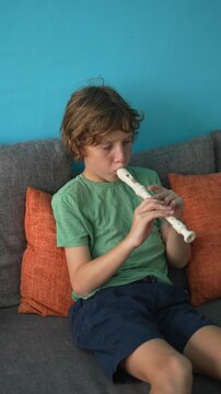 A little boy learns to play the flute at home, practicing with focus and enthusiasm in a cozy, warm setting. A charming scene of early musical exploration, creativity, and childhood growth.