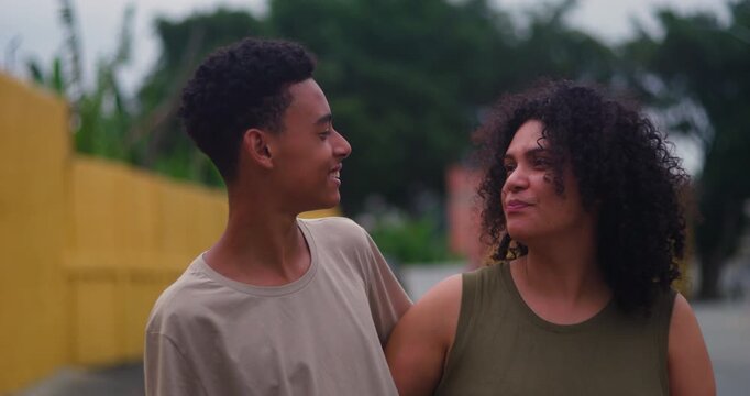 Teenage son looking warmly at his mother while sharing a joyful moment outdoors, showcasing love and mutual respect in a suburban setting