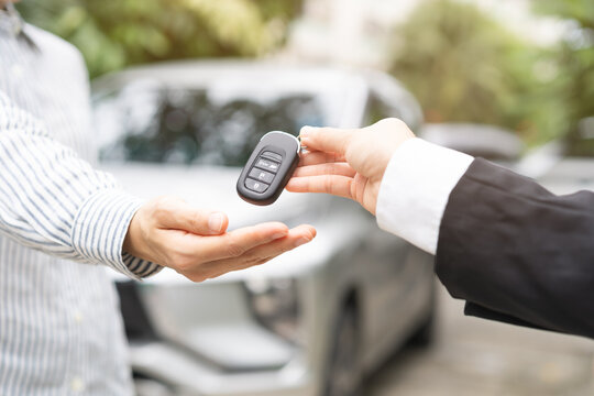 Close up of car dealer rental agent handing remote key to buyer or client leasing new automobile vehicle asset,
customer buying vehicle, car service automotive industry transport and insurance concept