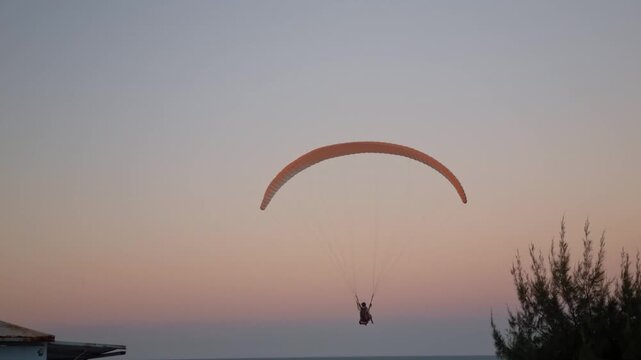 Paraglider soaring in the sky at dusk near Canoa Quebrada cliffs, aerial extreme sport