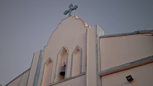 Old catholic chapel bell tower and christian cross against dusk sky, Canoa Quebrada