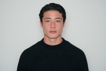 Obraz premium Portrait of a young man with freckles wearing a black sweater against a plain white background