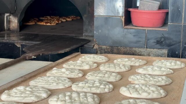 Fresh flatbreads baking in a traditional stone oven. Turkish pide. Turkish pide during Ramadan. 4K video.