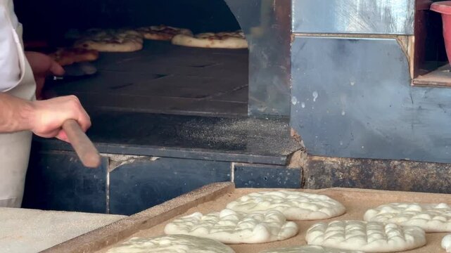 Fresh flatbreads baking in a traditional stone oven. Turkish pide. Turkish pide during Ramadan. 4K video.