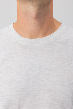 Close-up shot of a man's neck and the collar of a light grey heather t-shirt. Visible stubble and skin texture. Perfect for apparel mockups, fashion, grooming, and men's health content.