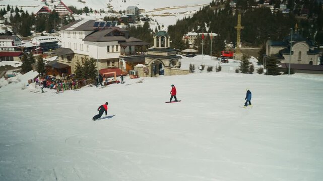 People enjoy skiing and snowboarding on a snow-covered mountain slope on a sunny winter day. Winter sports enthusiasts participate in outdoor recreational activities at a ski resort.
