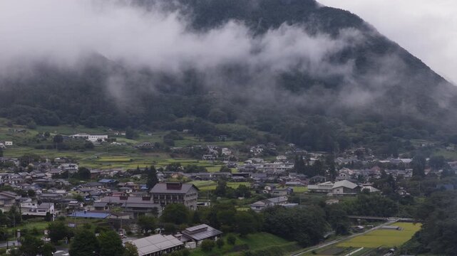 Fog, low cloud, and smoke over rural village in mountains of Nagano, Japan - Aerial view