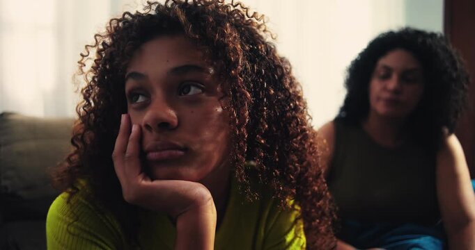Frustrated mother watching teenage daughter roll her eyes in disinterest, showcasing family conflict, strained communication, and emotional challenges, African descent
